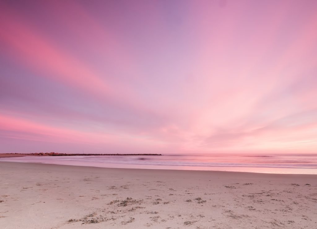 Rosaroter Himmel über einem Sandstrand