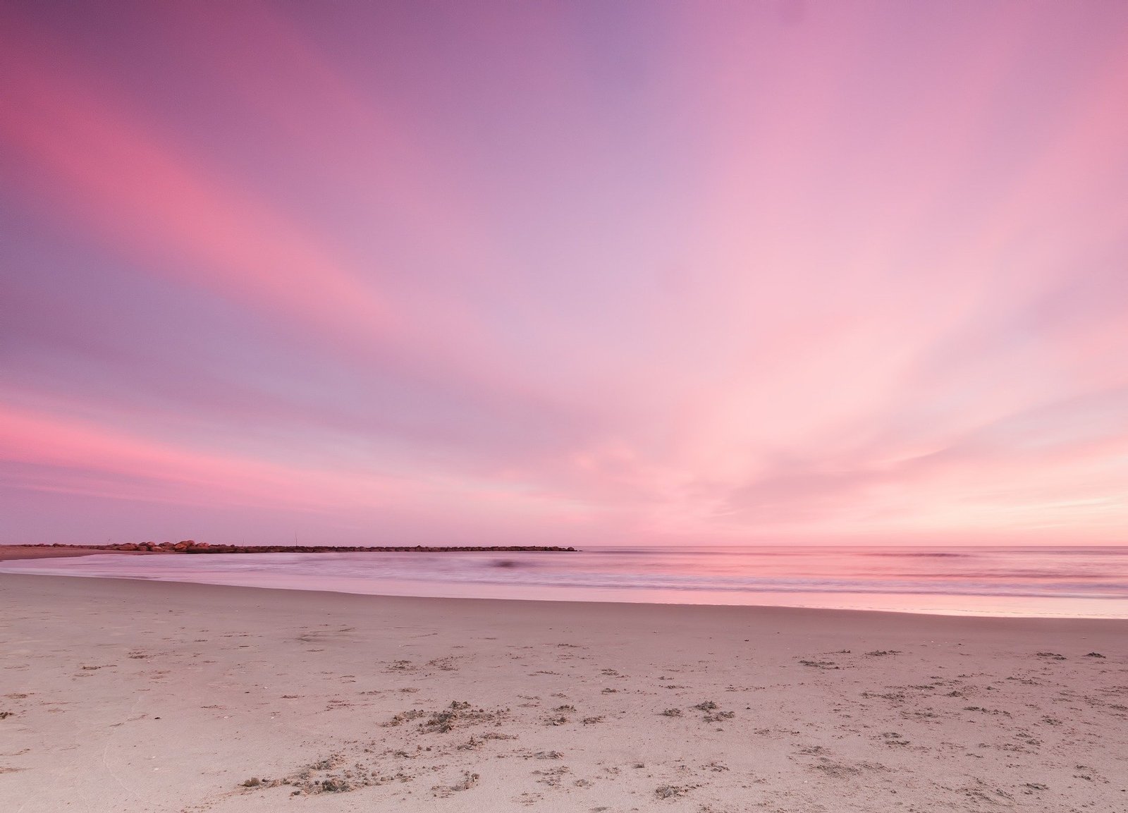 Rosaroter Himmel über einem Sandstrand