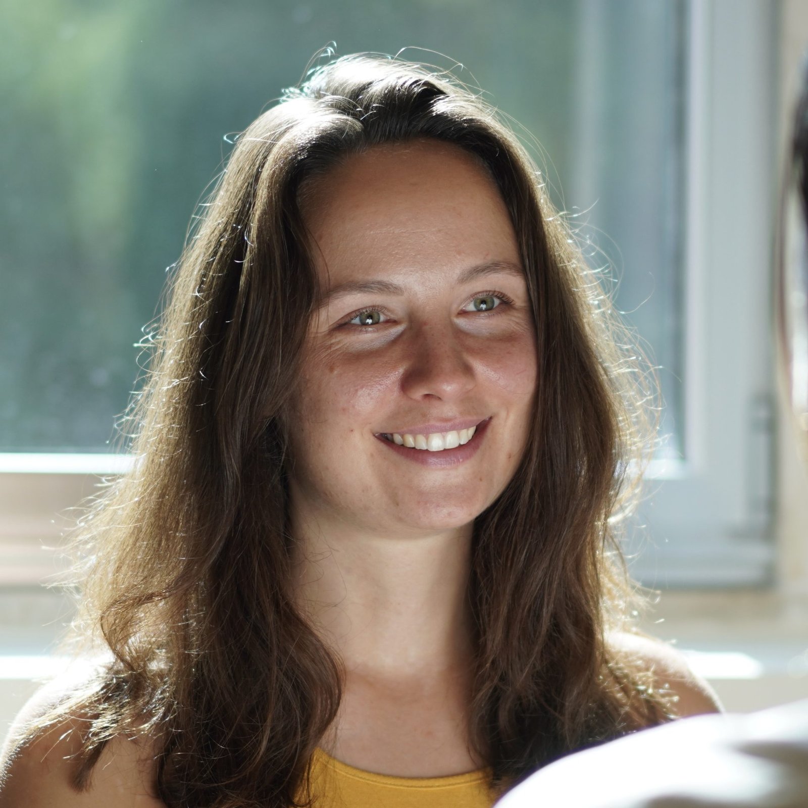 Lena lächelt im Sitzen einen Kunden im Tantramassage Studio in Berlin an