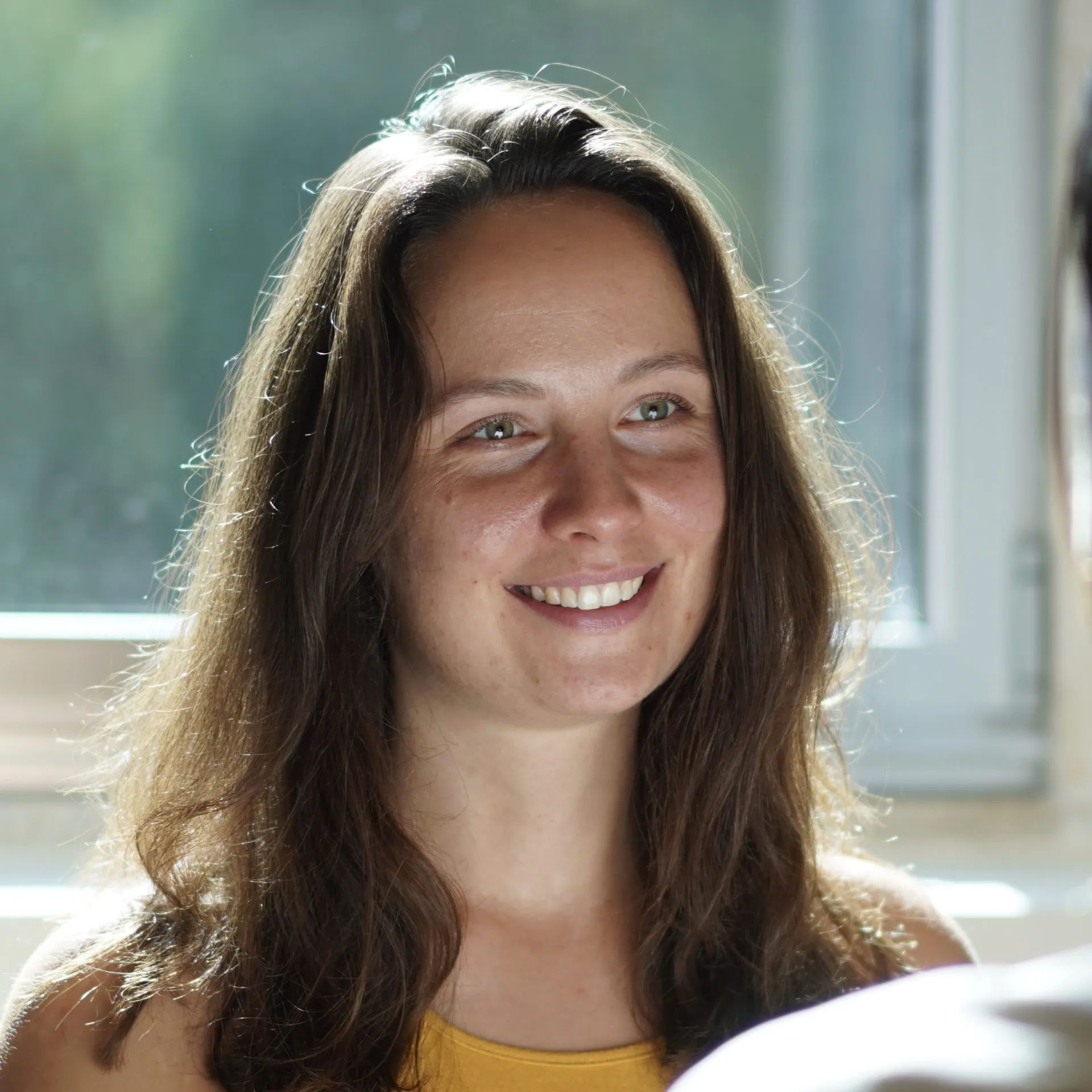 Lena lächelt im Sitzen einen Kunden im Tantramassage Studio in Berlin an