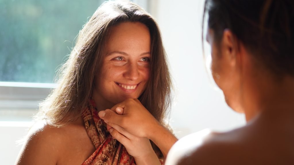 Masseurin beginnt Tantramassage mit einem Handkuss und lächelt